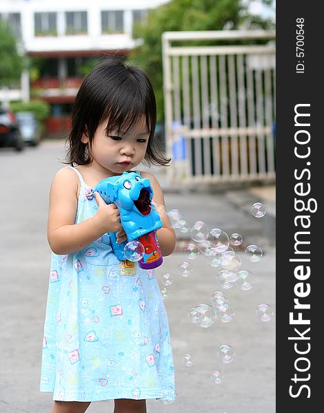 Asian little girl playing bubbles gun. Asian little girl playing bubbles gun.