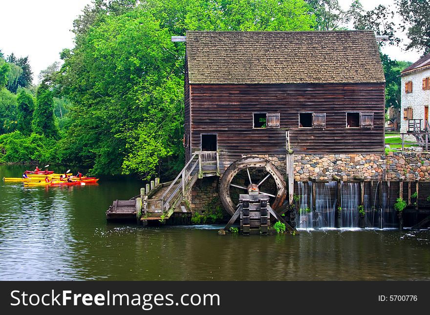 View of vintage river mill with water wheel and kayakers.