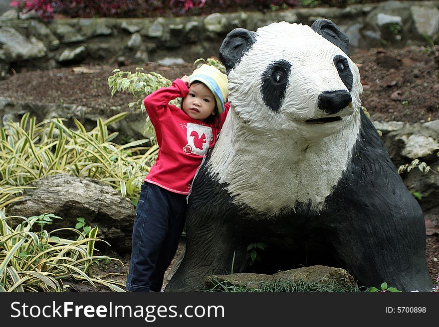 Asian little girl standing with panda statue.