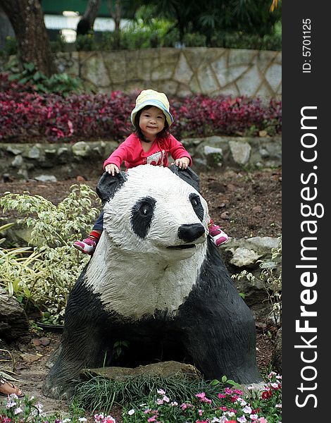 Asian little girl sitting on panda statue. Asian little girl sitting on panda statue.