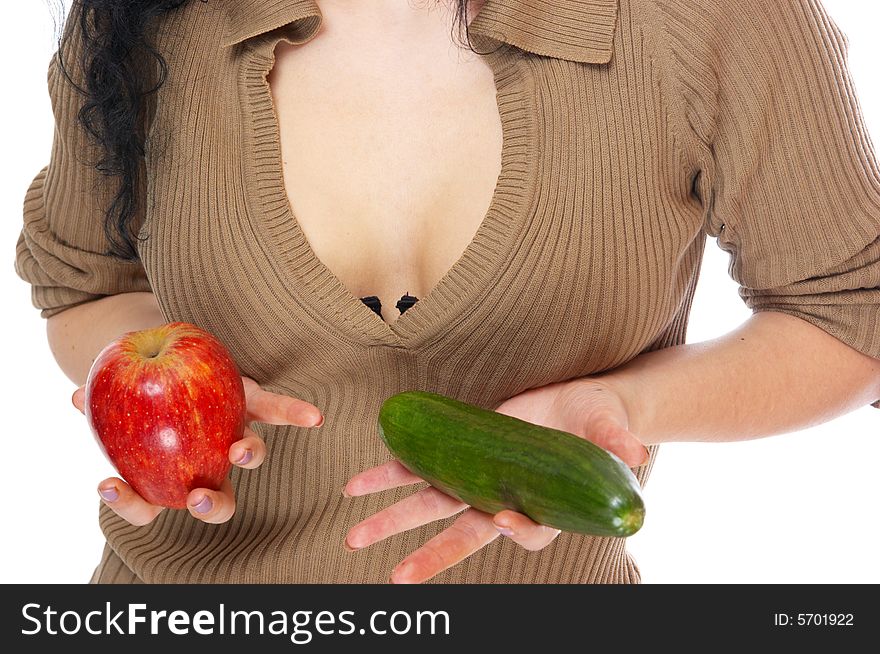 The girl holds an apple and a cucumber