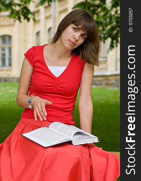 A beautiful young college girl reading a book outdoors. A beautiful young college girl reading a book outdoors
