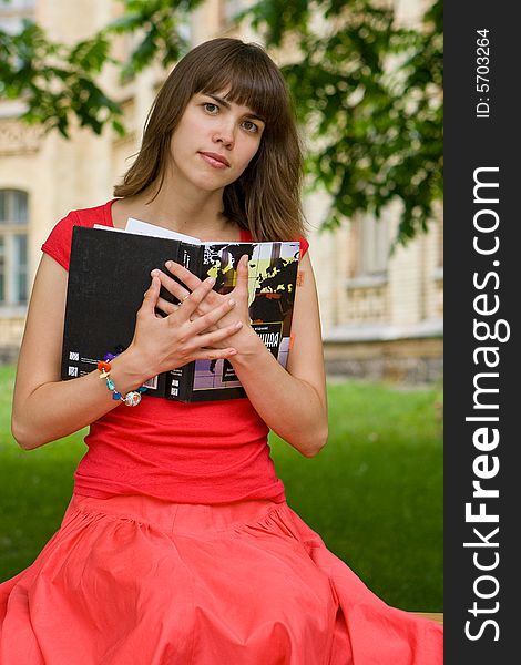 A beautiful young college girl holding a book. A beautiful young college girl holding a book