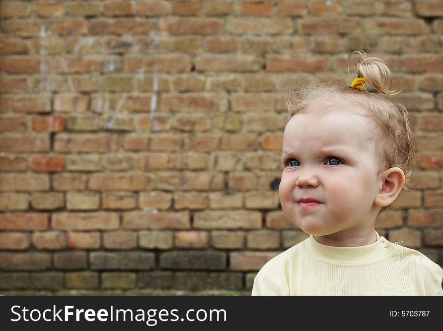 An image of baby-girl near a brick wall. An image of baby-girl near a brick wall