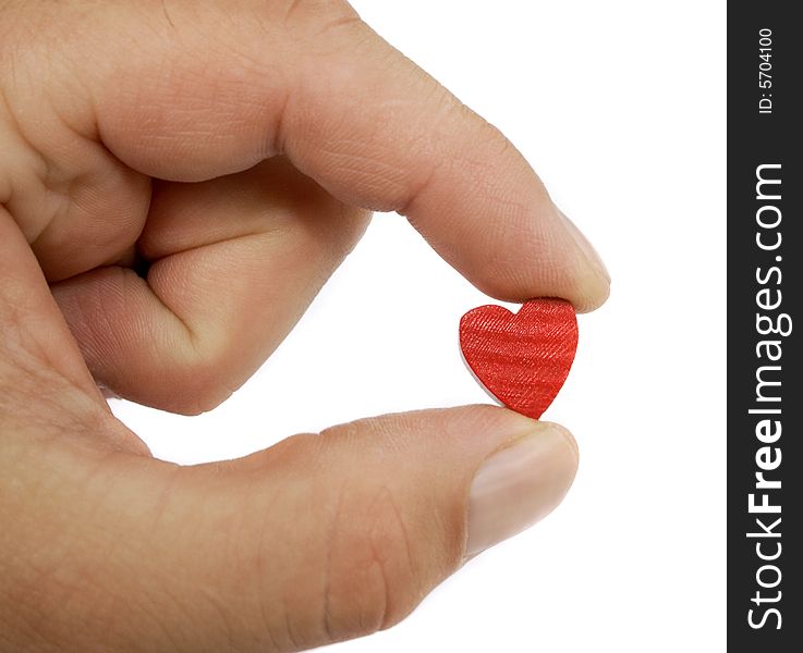 A hand shows a small wood and painted red heart between it's two fingers in front of a white background. A hand shows a small wood and painted red heart between it's two fingers in front of a white background.