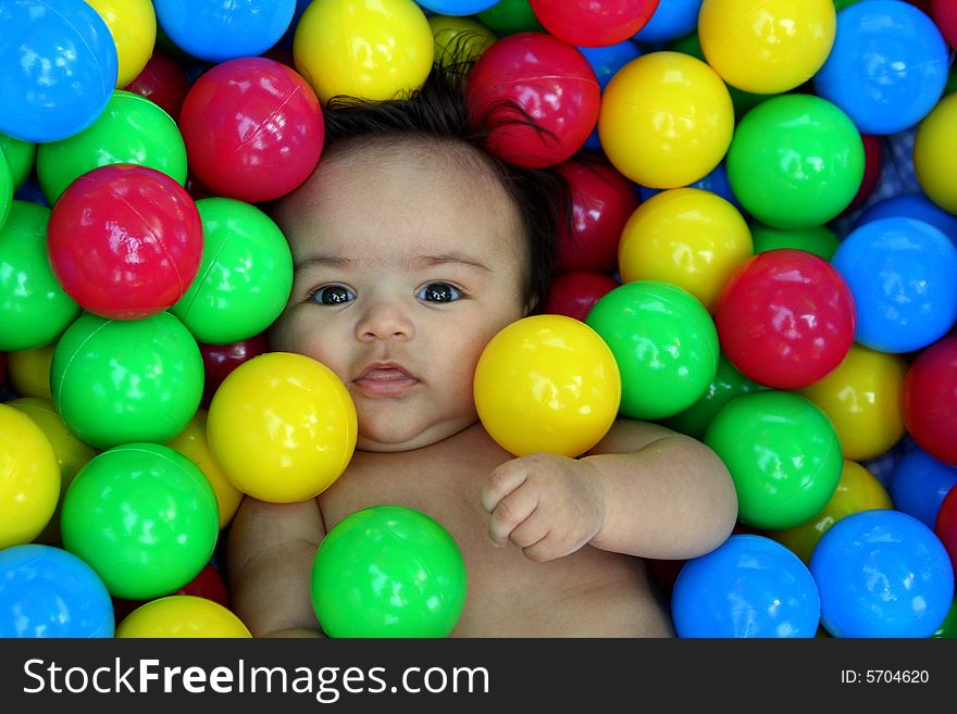 A newborn baby boy playing with colorful balls. A newborn baby boy playing with colorful balls.