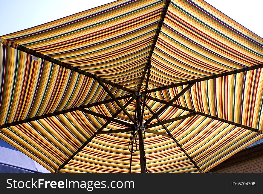 A colorful striped sun umbrella backlit by the sun. A colorful striped sun umbrella backlit by the sun