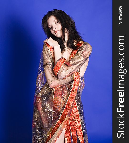 Beautiful young woman embracing herself wearing a partially see-through oriental style robe.