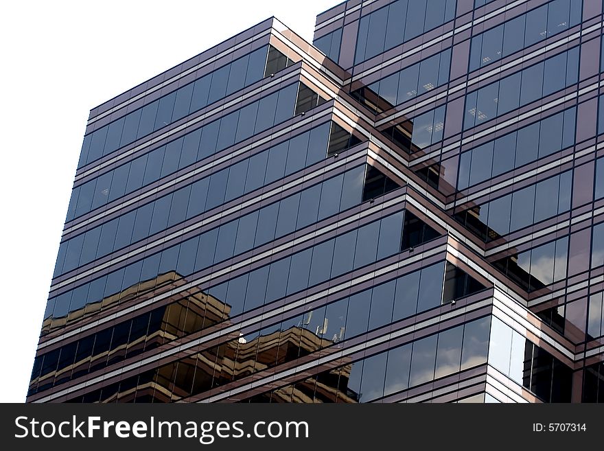 A glass modern building reflecting the sky and other buildings isolated on white. A glass modern building reflecting the sky and other buildings isolated on white