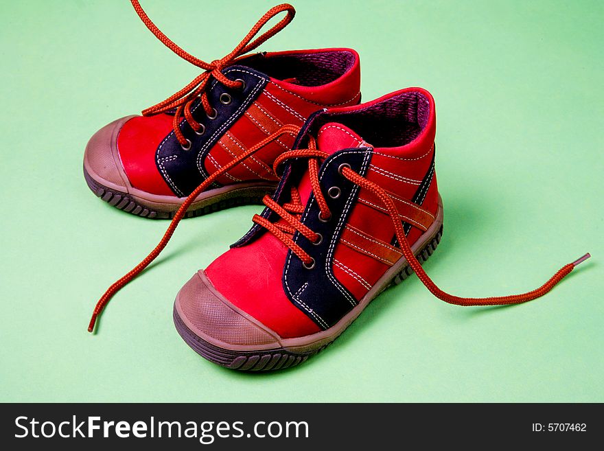 Red children's shoes on green background. Red children's shoes on green background