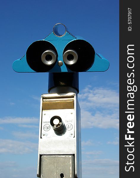 Coin-operated tourist binoculars over blue sky. Coin-operated tourist binoculars over blue sky