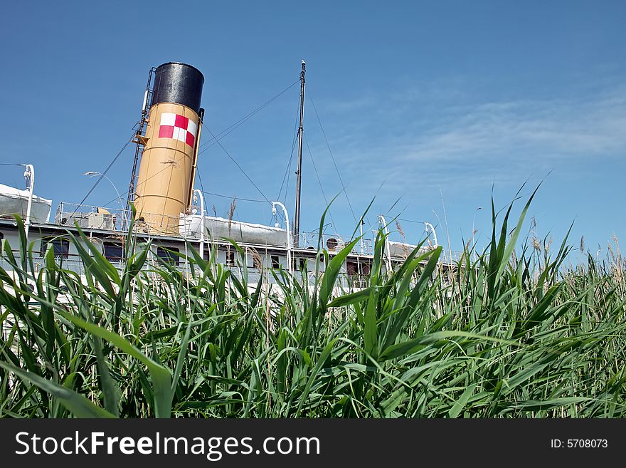 A 1907 Great Lakes Steam Ship as seen though the long grass near the ships dock. A 1907 Great Lakes Steam Ship as seen though the long grass near the ships dock