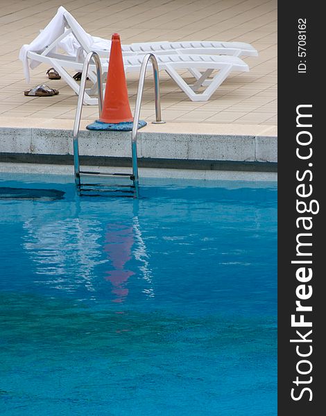 Abandoned beach chair next to a closed pool. Abandoned beach chair next to a closed pool.