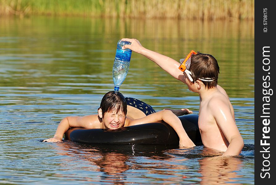 The boy pouring water from the bottle on his friends' head. The boy pouring water from the bottle on his friends' head.