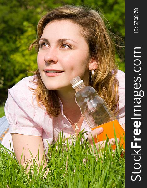 Woman drinking juice on green grass