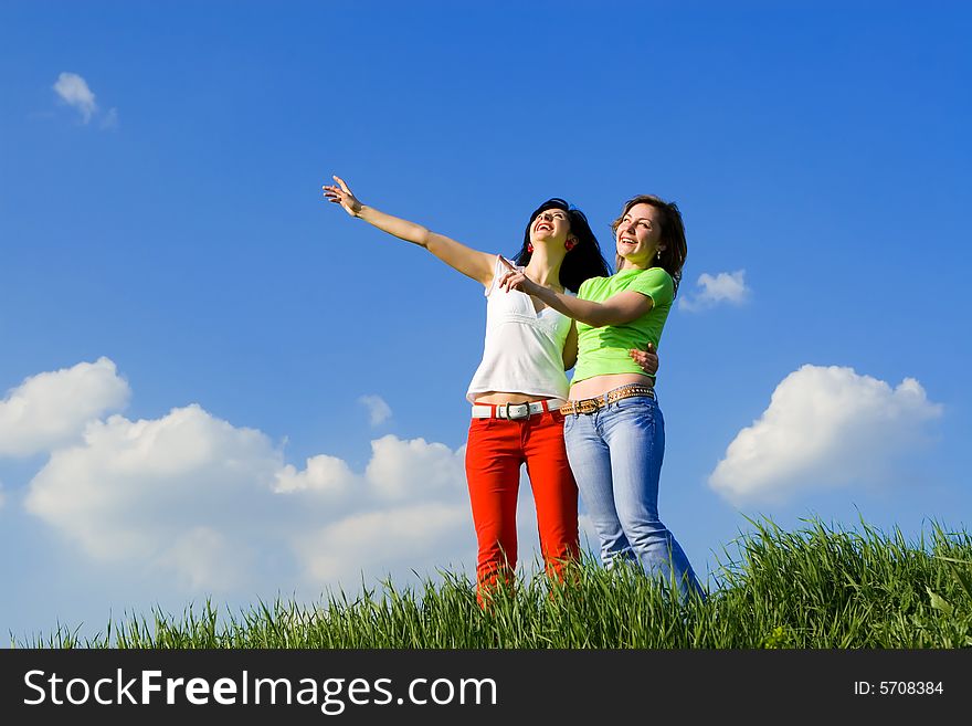 Two young women on a green meadow and show something