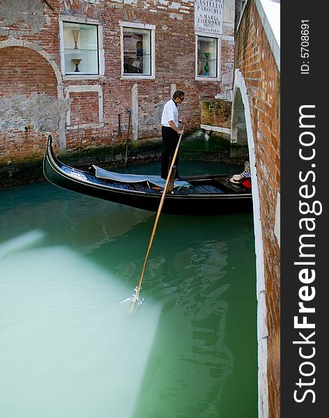 Venetian gondolier on his gondola in a waterway if Venice