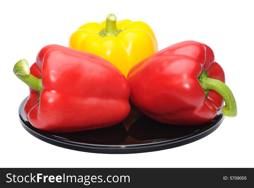 Red and yellow peppers on a black dish isolated on white
