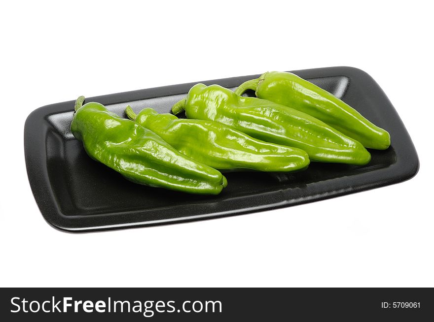 Green peppers on a black dish isolated over white background