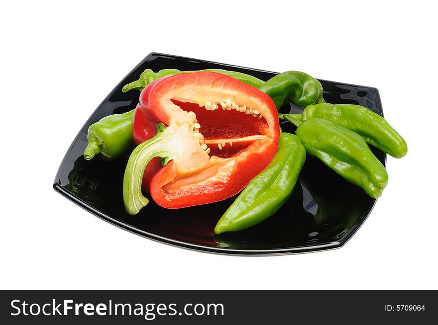 Sliced red and green peppers on black dish isolated over white background. Sliced red and green peppers on black dish isolated over white background