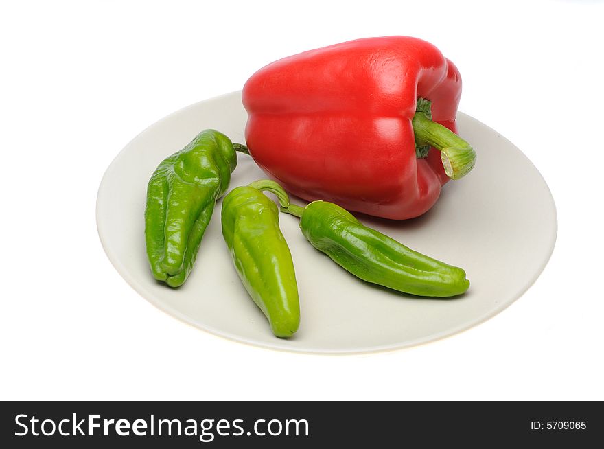 Fresh raw peppers on a dish isolated over white background. Fresh raw peppers on a dish isolated over white background