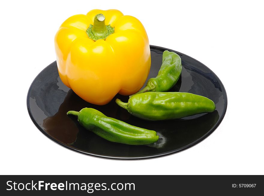 Yellow and green peppers on black dish isolated over white background. Yellow and green peppers on black dish isolated over white background