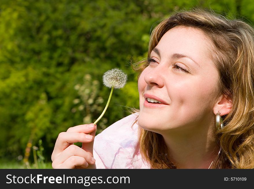 Happy girl blowing on the dandelion