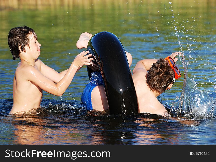 Two friends are playing with a tube in a small lake late afternoon. Two friends are playing with a tube in a small lake late afternoon.