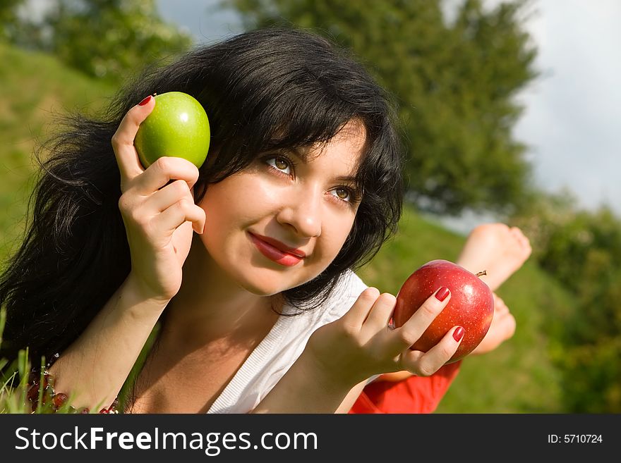 Pretty woman eating apple on the summer glade