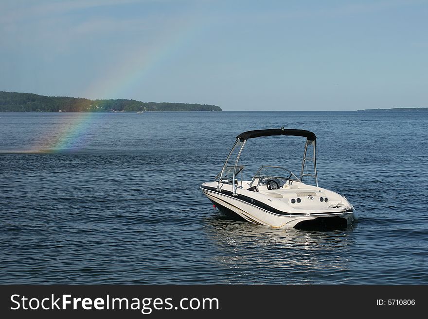 A rainbow appears beside a small boat on a sunny afternoon. A rainbow appears beside a small boat on a sunny afternoon