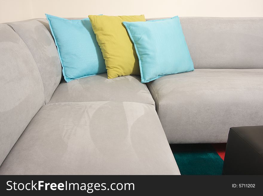 Grey Suede Couch Corner Area with colorful rug and pillows.