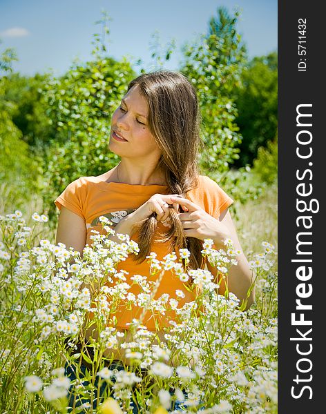 Cute girl braid one's hair in camomile field. Cute girl braid one's hair in camomile field