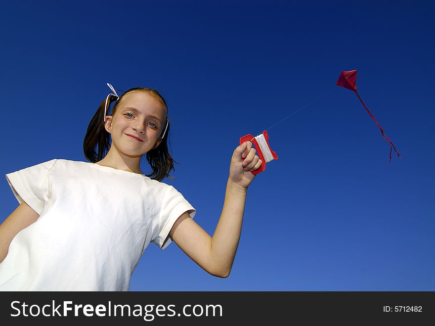 Girl flying a kite in a park with blue sky
