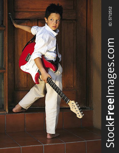 Boy standing up opening door with red guitar. Boy standing up opening door with red guitar