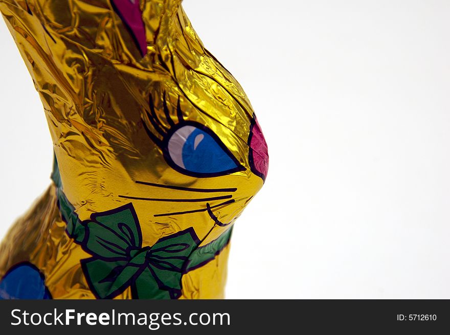 A golden-wrapped chocolate easter bunny on a white background.