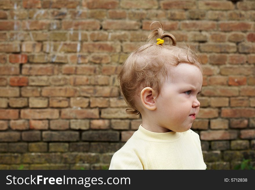 An image of baby near a yellow brick wall. An image of baby near a yellow brick wall