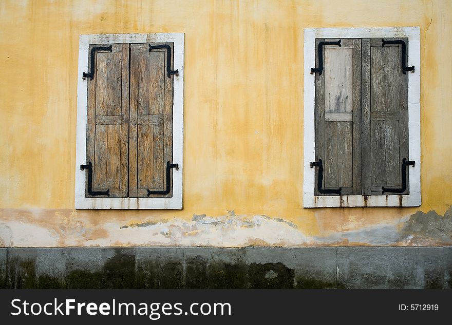 An image of wooden windows closed on yellow wall