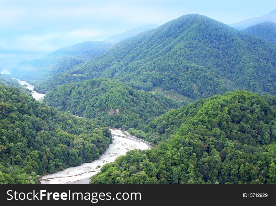 Mountain tops and river on background blue year sun