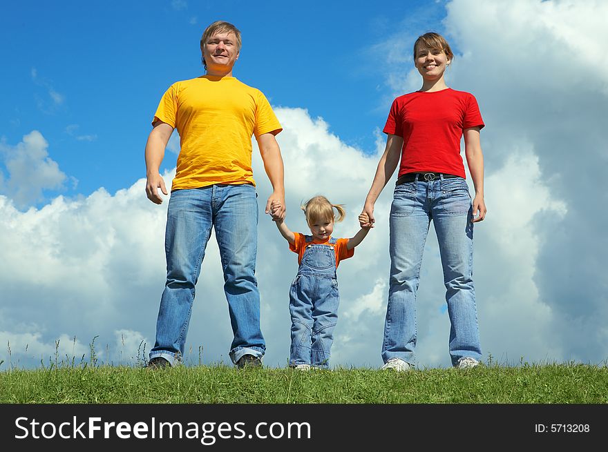 Happy family stand on green grass under sky with clouds