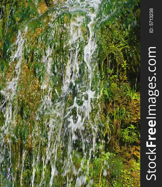 Small waterfall details with lush green vegetation