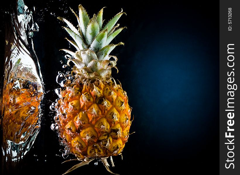 Fresh pineapple in water on a black/blue background with air bubbles