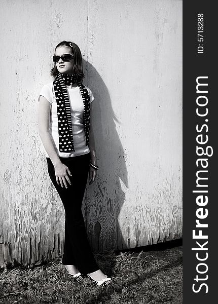 Attractive preteen girl standing against a weather wall.  Bright sunlight with shadows included for effect. Attractive preteen girl standing against a weather wall.  Bright sunlight with shadows included for effect.