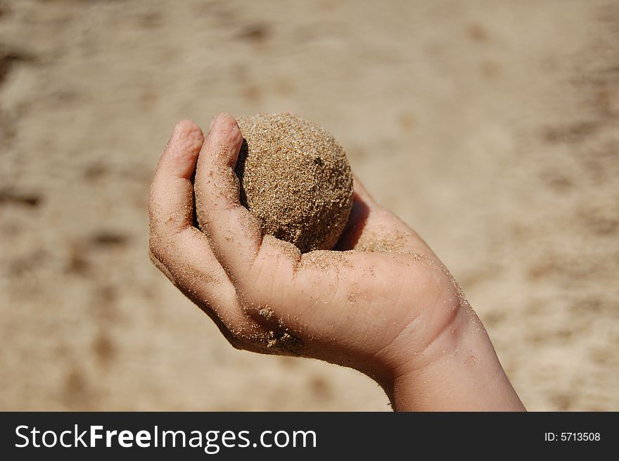 Small Child's hand holding wet sand ball