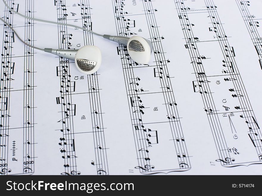 White earbuds laying on page with sheet music. White earbuds laying on page with sheet music