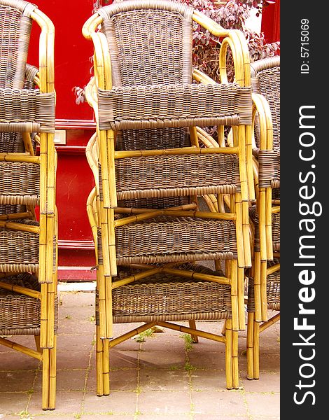 Stored chairs at a terrace in ftont of a red door