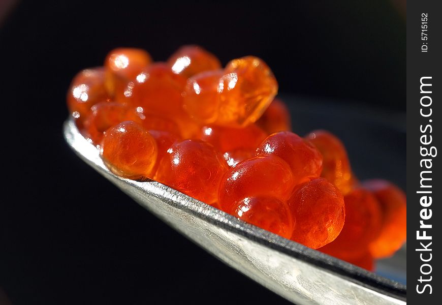 Red caviar on a spoon against black background. Red caviar on a spoon against black background