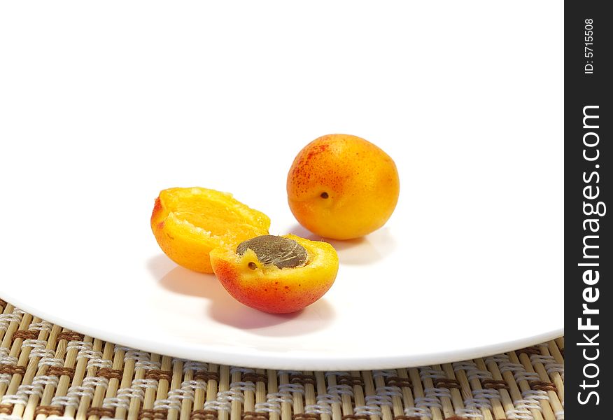 Ripe apricots and black currant on a white plate