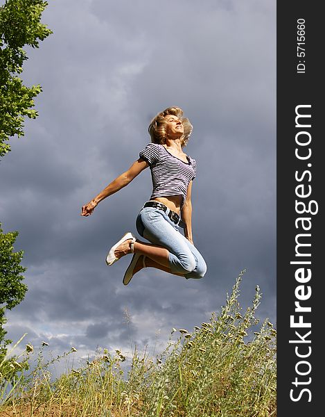 Beautiful young woman jumps. Sky as background