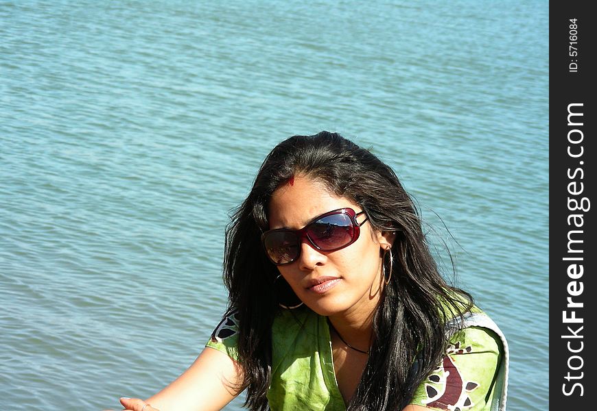 A portrait of a beautiful Indian Babe sitting by the lakeside thinking