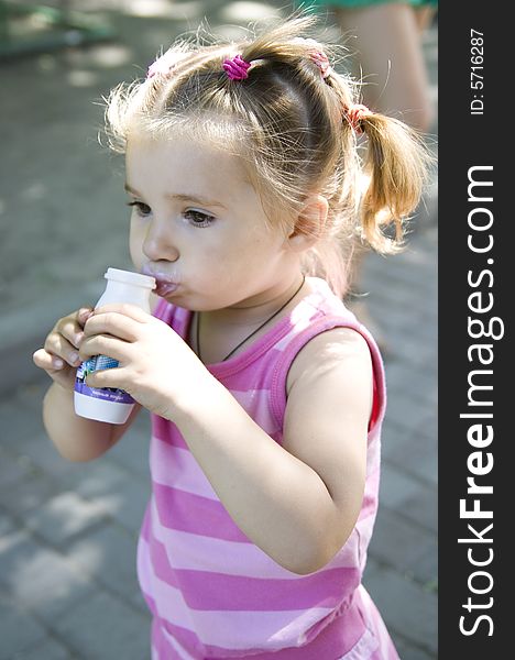 Little cute girl drinking yoghurt